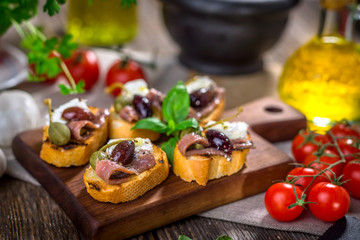 Fototapeta na wymiar Tasty bruschetta with anchovy, feta, caper, olive oil ...