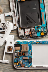 Disassembled parts of cell phone on wooden table