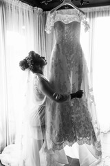 Black and white photo of stunning bride holding dress in her arm