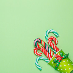 Top view of a colorful candy cane in a green glass on a pastel green background. Minimal style