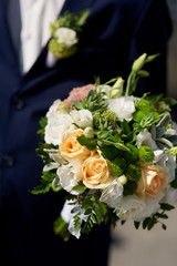 groom holds the brides wedding bouquet
