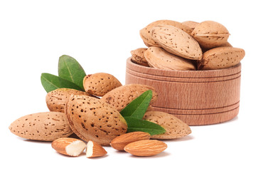 Almonds in a wooden bowl with leaves isolated on white background