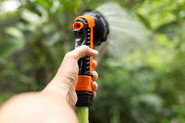 Naklejka premium Gardener watering plant with hose