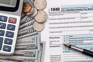 U.S. 1040 tax return form with dollar, pen and calculator.