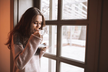 Pretty lady sitting at table in cafe while drinking coffee