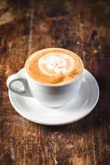 cup of coffee with bear pattern in white on wooden background