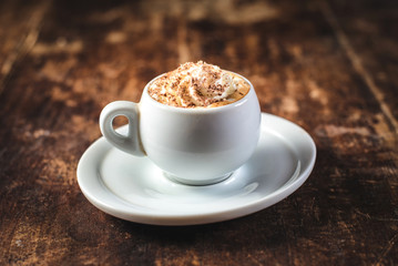 Cup of coffee with ice cream and chocolate on wooden background