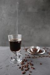 Hot coffee in the tall glass with cold milk on the grey stone table