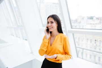 Fototapeta premium Business woman standing near the window with phone