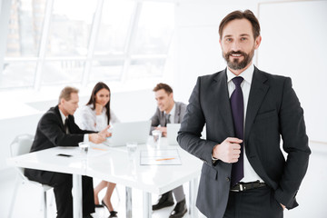 Bearded Business man with colleagues on background