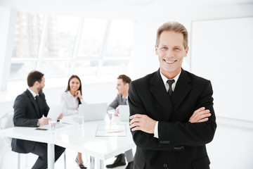 Smiling Elderly Business man with colleagues on background