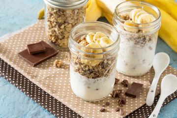 Granola. Granola with yogurt, chocolate and banana on blue concr
