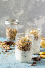 Granola. Granola with yogurt, chocolate and banana on blue concr