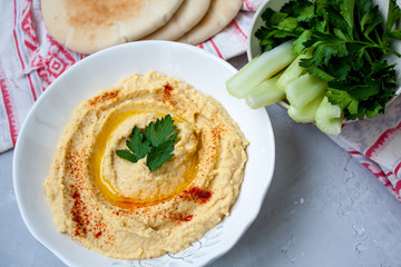 Home classic hummus with celery, pitoy.Vid top on gray concrete background. Vegan Food Concept.