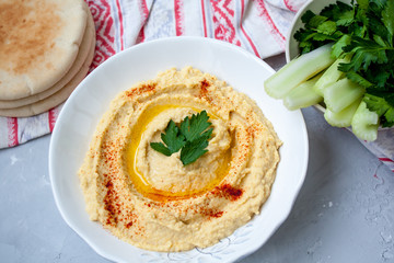 Home classic hummus with celery, pitoy.Vid top on gray concrete background. Vegan Food Concept.