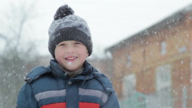 winter boy waved a hand/portrait of a cheerful boy in winter when snow falls