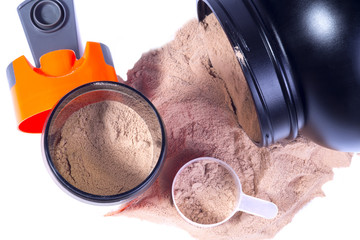 Sport nutrition image. Whey chocolate protein powder poured from protein jar, opened orange sport shaker near with milk and protein, scoop with powder near. Close up image. White background.
