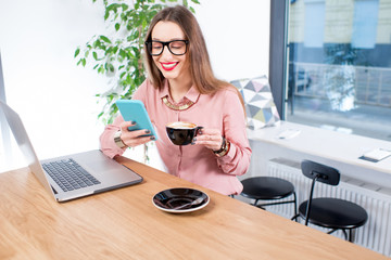 Businesswoman sitting with coffee, laptop and smart phone at the modern cafe interior