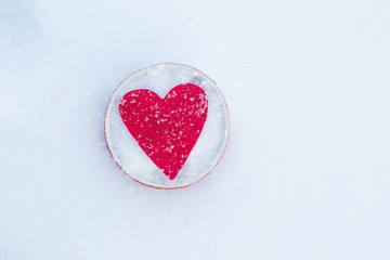 Red felt heart shape in a bowl in snow, Valentine's Day. Copy space for text. Snowflakes on heart. Valentines day, love concept. White background