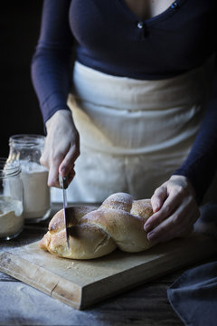 Woman cutting fresh braided bread