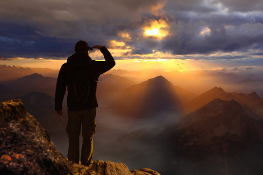 Man standing on a mountain watching sunset sunrise