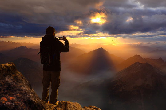 Wanderer auf Berggipfel macht Foto mit Smartphone