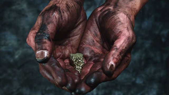 4k Technical Composition of Dirty Mechanic Hands Holding Gold Rock