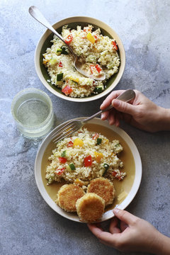 Female hand holding a plate with sauteed vegetables couscous sal
