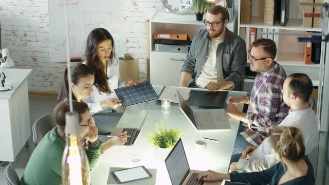 Group of Young Creative People Have Strategic Planning Session about Solar Panel Technology. They are Sitting at Big Glass Table with Open Laptops in their Bright Office.  Shot on RED EPIC (uhd). 