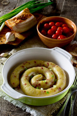 Homemade baked sausage with potatoes and bacon on a rustic backg