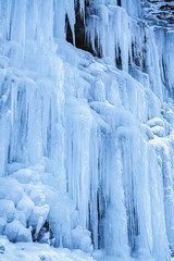 Frozen icicles on rocky wall at the mountain, closeup with selec