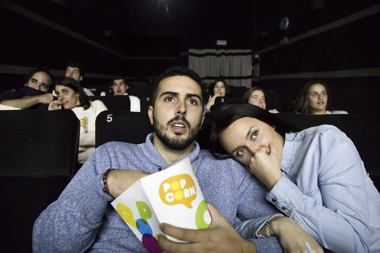 Scared couple watching a movie in a cinema