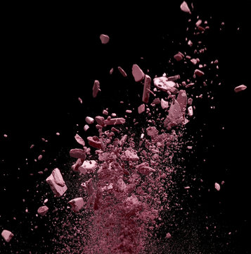Close up of pink crushed powder cosmetics against black background