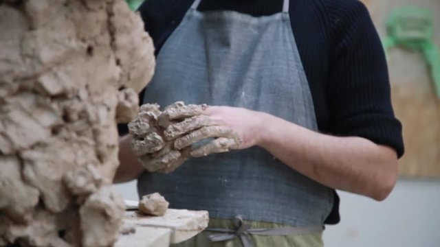 Sculptor modelling sculpture adjusting face details head made of clay. Creative concept.