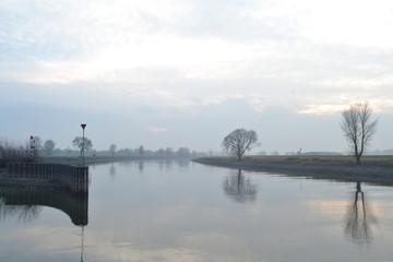 De rivier de IJssel stroomt op een nevelige dag langs de haven van Doesburg
