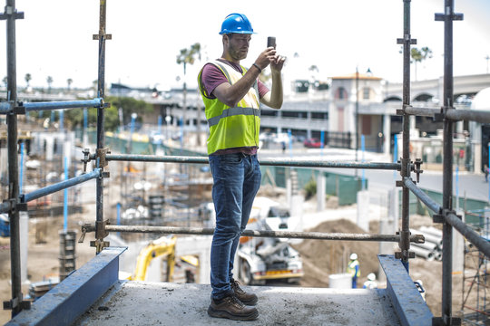 Construction worker on construction site taking pictures with smart phone