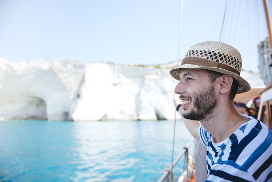Greece, Milos, Man with straw hat on sailing boat