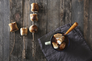 Hot chocolate with fire-roasted marshmallows on wooden table