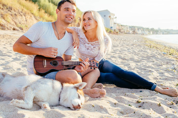 couple playing guitar on beach