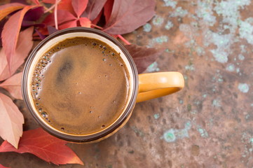 Cup of coffee in and red autumn leaves