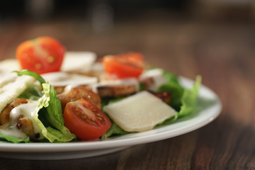 caesar salad with cherry tomatoes on wooden table