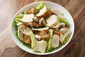 shot of caesar salad with chicken in white bowl