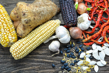 Corns, potato, garlic, pumpkin seeds, beans and red chilies on old bark 