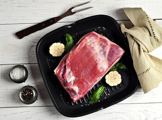 Fresh raw bacon with garlic, salt and pepper in a pan grill.