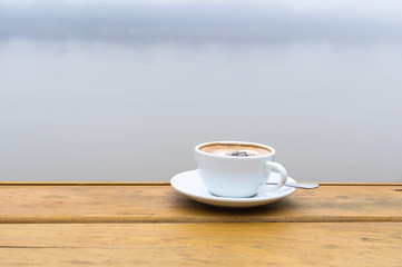White coffee cup on wood table beside the river view