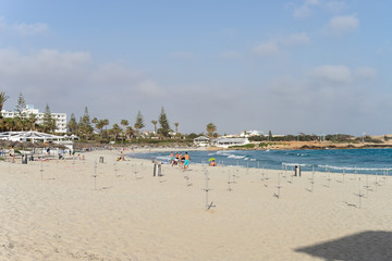 People sunbathe on Nissi Beach sand at sunny day. Ayia Napa, Cyprus.