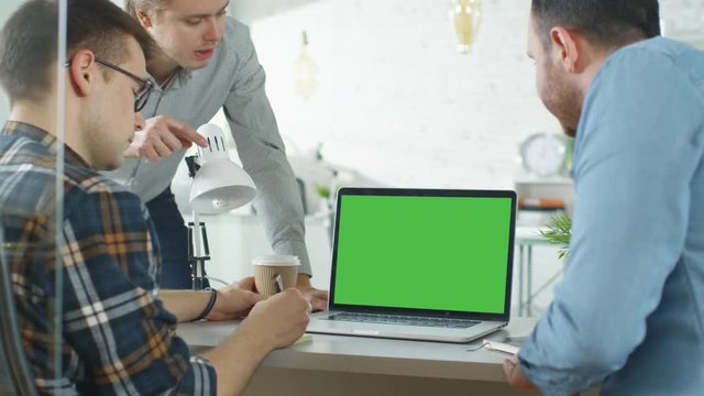 Three Creative Men Discuss Business around Green Screened Laptop. They're in Bright Modern Office.  Shot on RED EPIC (uhd).