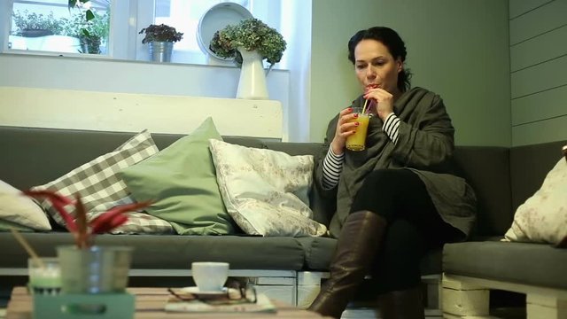 Young woman drinking orange juice in cafe