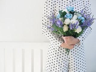 Close-up of young woman in dot pattern dress and  hold blue flowers .