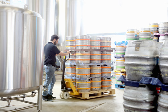 Worker in brewery organising beer barrels for delivery